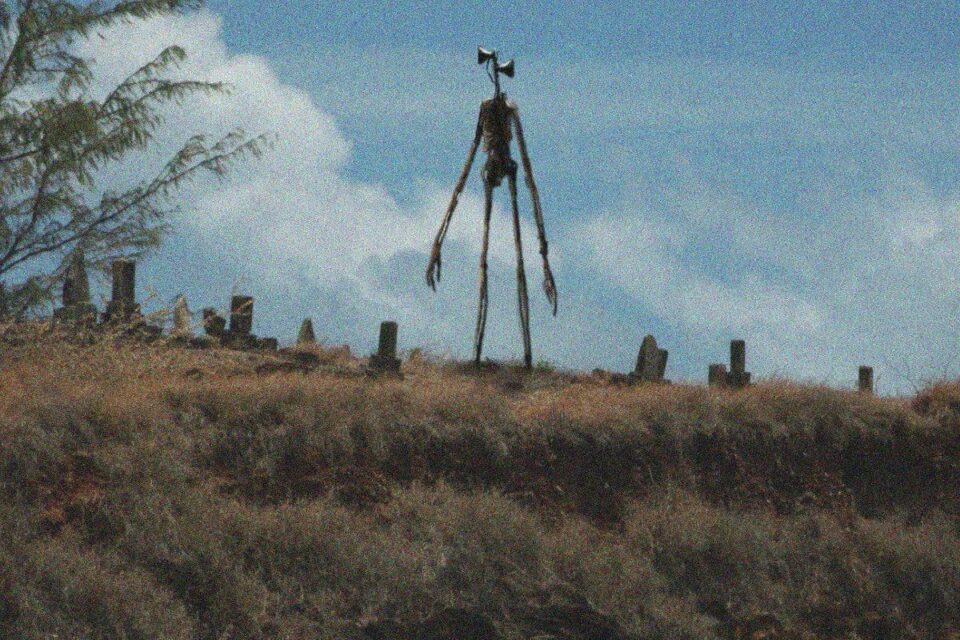 La créature Siren Head, silhouette squelettique géante avec une tête en forme de sirènes, dans un cimetière